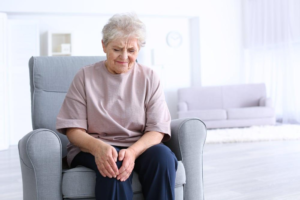 Elderly woman sitting comfortably at home, reflecting and enjoying her time.