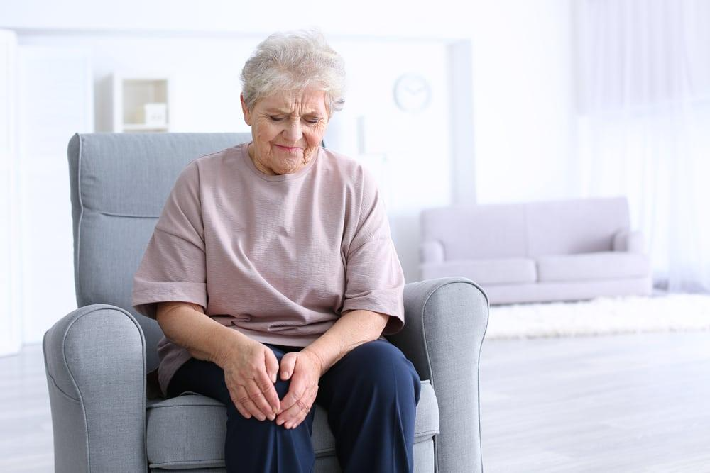 Elderly woman sitting comfortably at home, reflecting and enjoying her time.