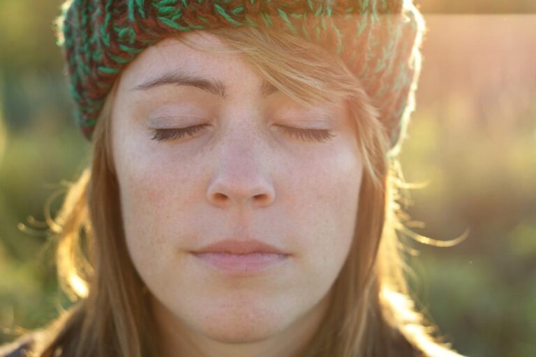 Serene woman meditating outdoors, basking in warm golden sunlight.