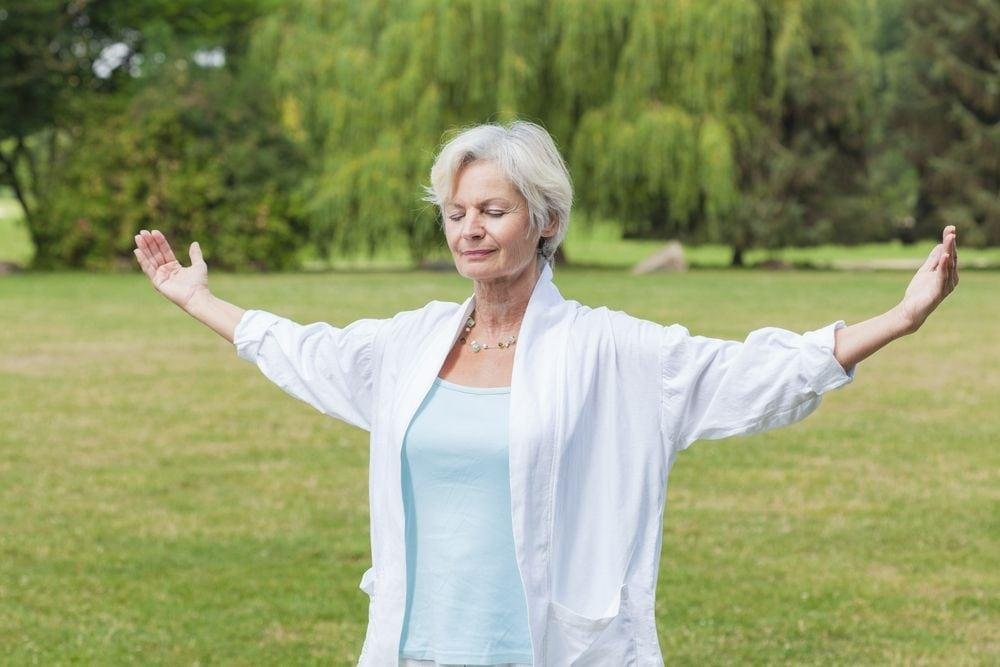 Senior woman practicing yoga outdoors, promoting relaxation and mindfulness in nature.