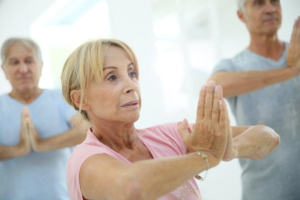 Seniors practicing yoga together in a bright, peaceful studio setting.