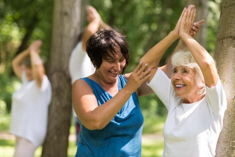 Seniors enjoying outdoor fitness activities with enthusiastic instruction.