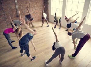 Students participating in a group stretching exercise class indoors.