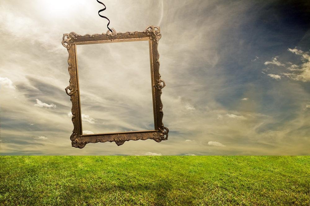 A decorative frame suspended in serene, open nature under a dramatic sky.