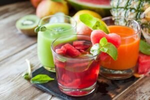 Colorful fruit juices in glasses with fresh ingredients and vibrant garnishes.