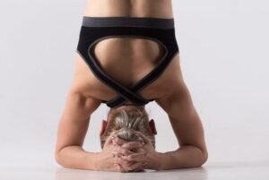 Yoga practitioner performing a headstand pose on a mat, showcasing balance and strength.