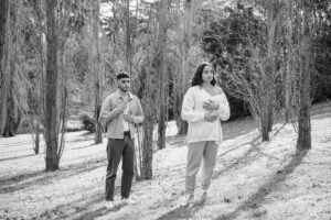 Two people walking in a serene black and white forest setting.