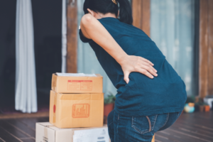 Person lifting boxes and experiencing back pain.