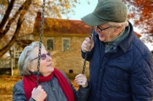 Senior couple enjoying a playful moment on a swing in autumn.