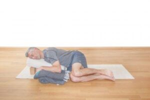 Senior man relaxing on yoga mat for mindfulness and stress relief.