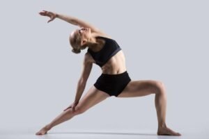 Flexible dancer performing a yoga pose against a grey background.