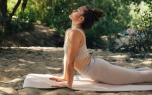 Woman practicing yoga outdoors in the sunshine, enjoying nature and tranquility.