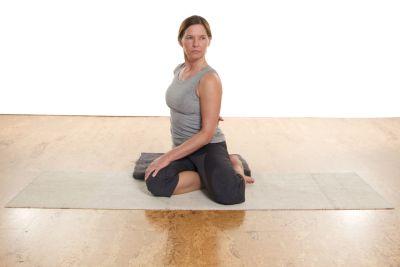 Woman practicing a seated yoga stretch on a mat for flexibility and relaxation.