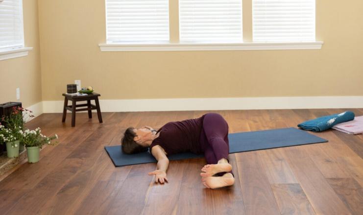 Relaxing yoga stretch for home practice on a mat.