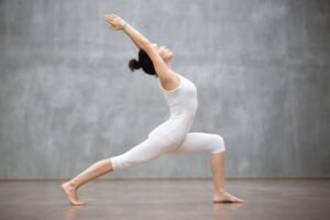 Woman practicing Warrior Pose in yoga class, focusing on strength and balance.