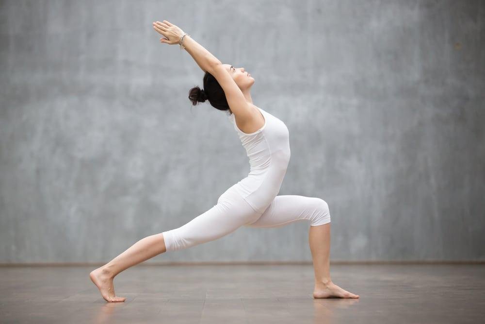 Woman practicing Warrior Pose in yoga class, focusing on strength and balance.