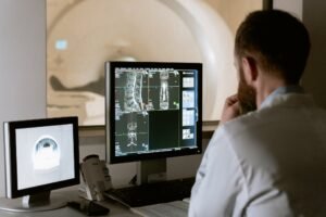 Doctor analyzing medical scans on dual monitors in a clinical setting.