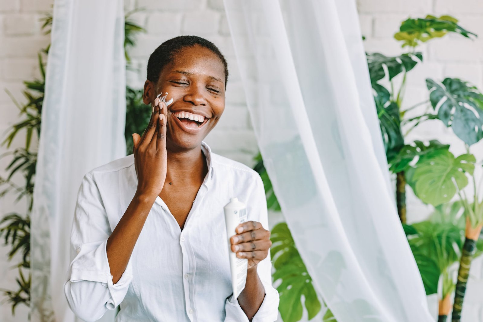 Smiling woman enjoying her skincare routine at home.