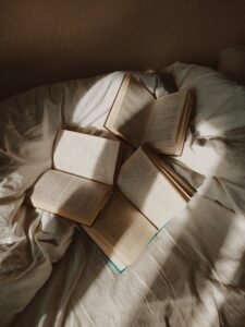 Open books scattered on a cozy bed with natural light.