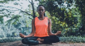 Woman meditating peacefully in a serene outdoor setting.