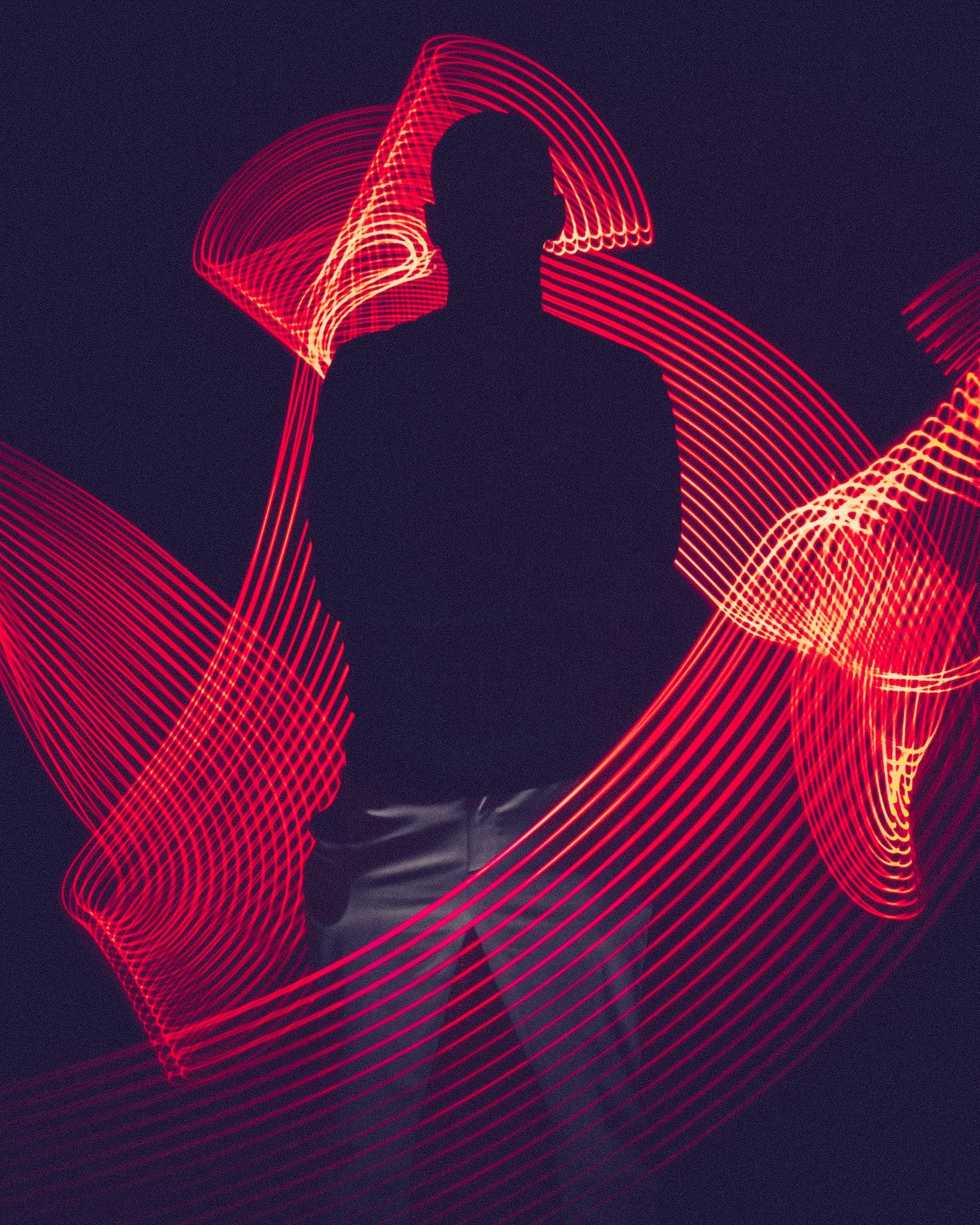 Silhouette of a man amidst flowing red LED light trails.