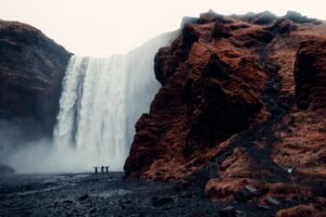 Men exploring a stunning waterfall in a rocky landscape.