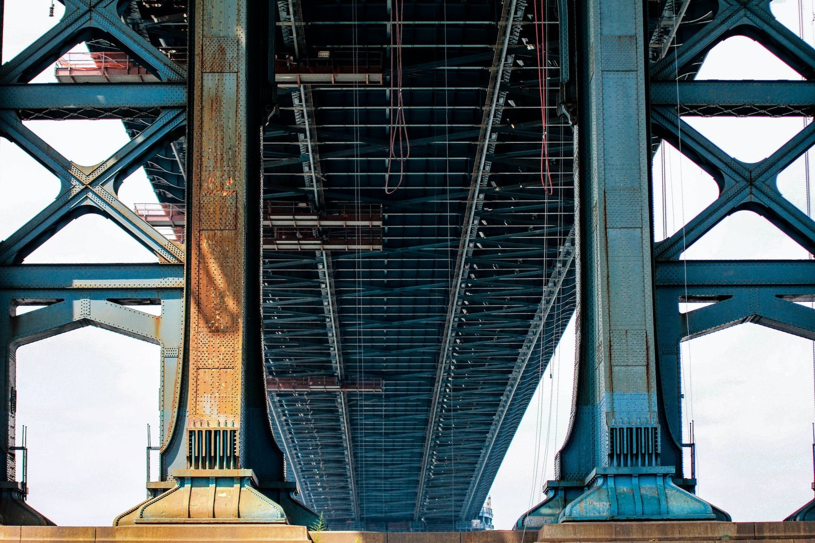 View of a blue metal bridge from below in bright daylight.