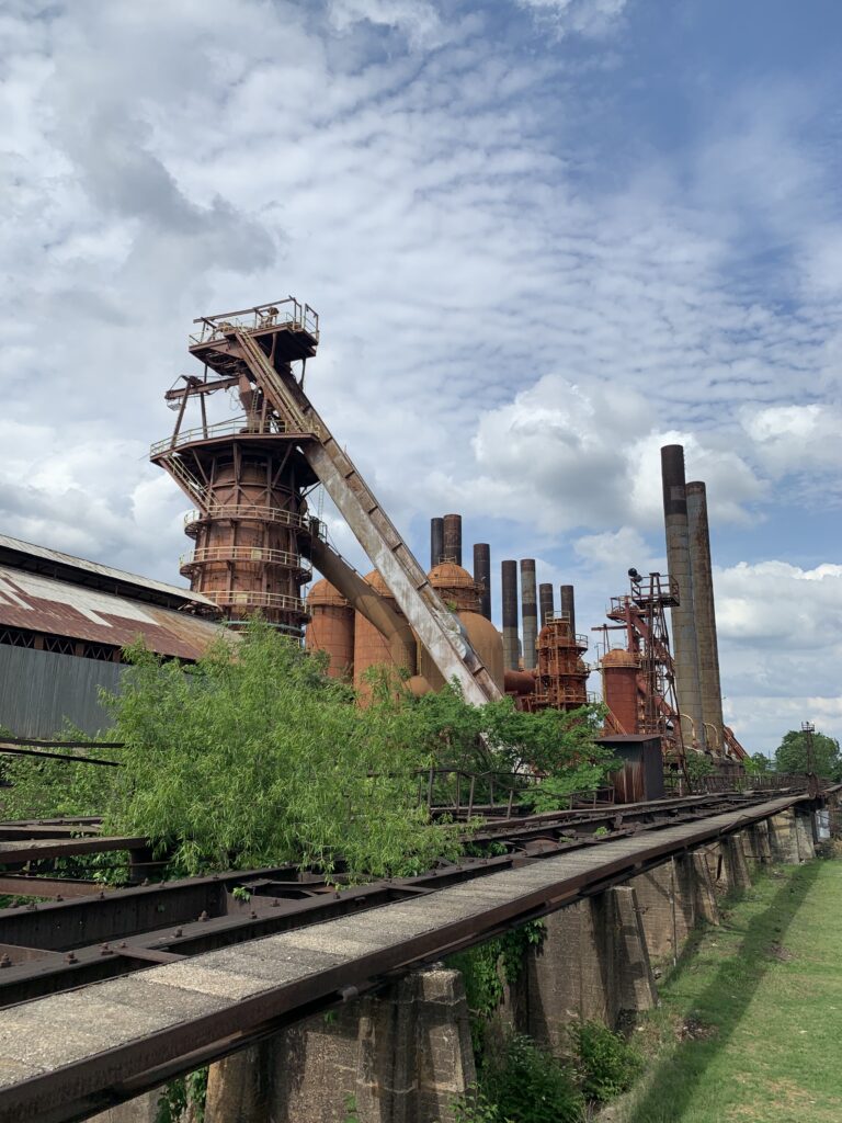 Historic Birmingham industrial furnaces against a vibrant sky with green surroundings.