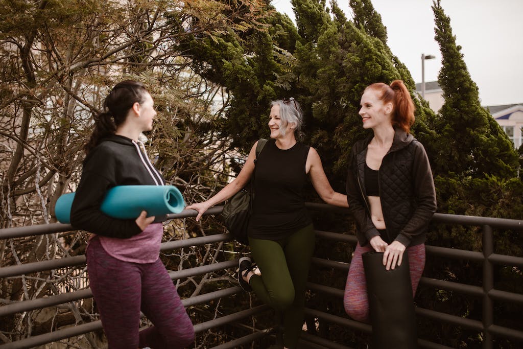 Women enjoying a friendly yoga session in nature, sharing laughter and positivity.
