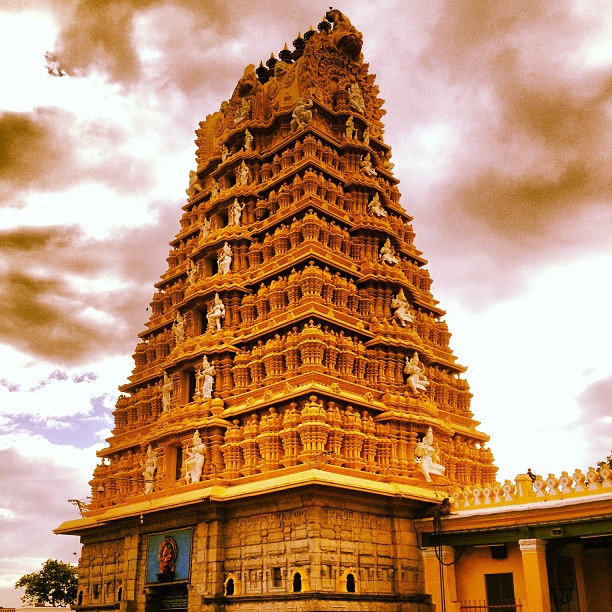 Stunning golden temple tower under dramatic skies in India.