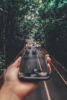 Innovative forced perspective photo of a smartphone above a busy tree-lined road.