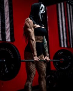 Strong woman lifting weights in a scream mask at the gym.